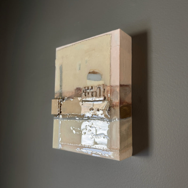 Abstract wall sculpture with reflective surface on a gray background